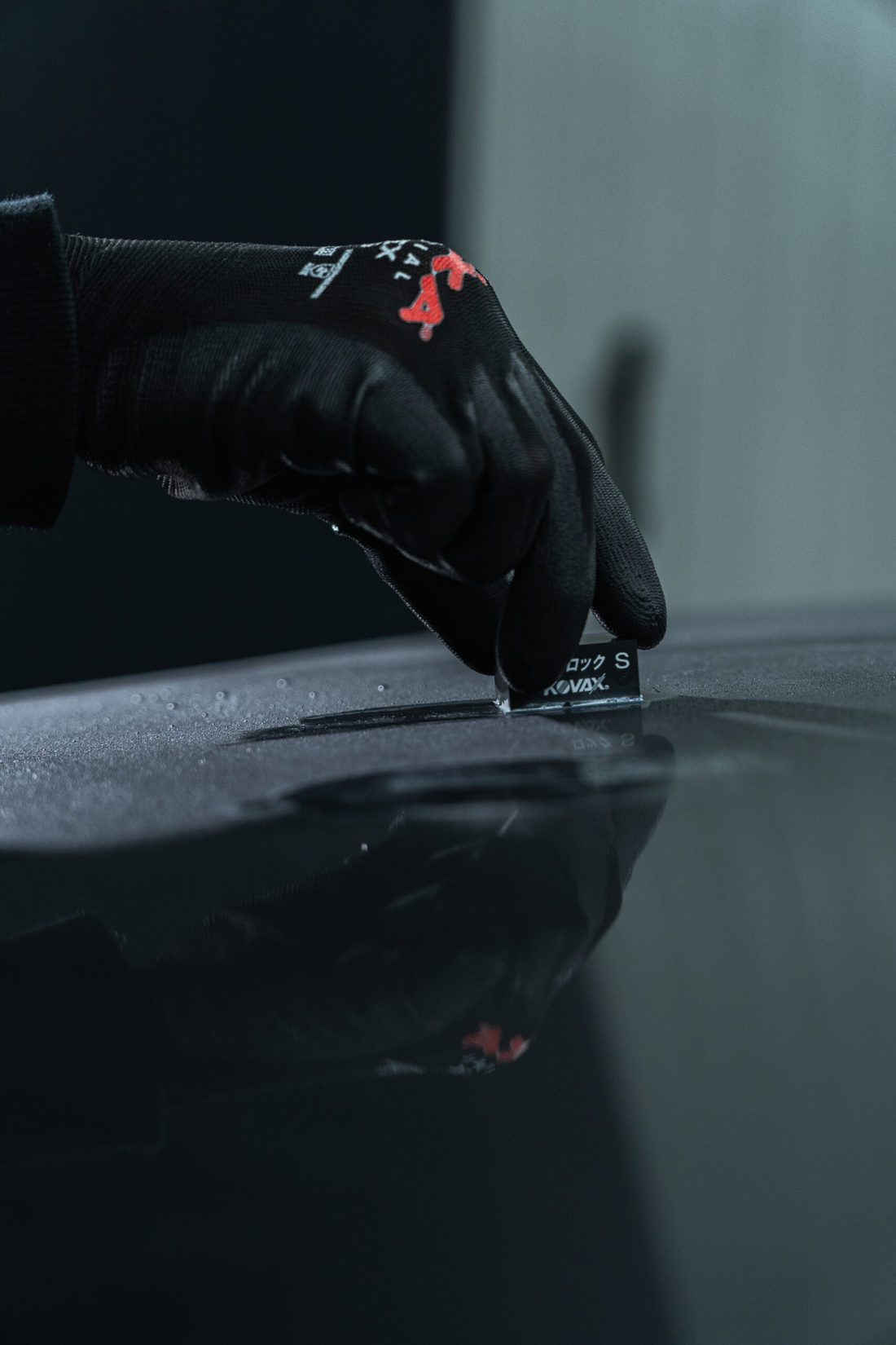 Handschoen brengt een coating aan op een donkere lak